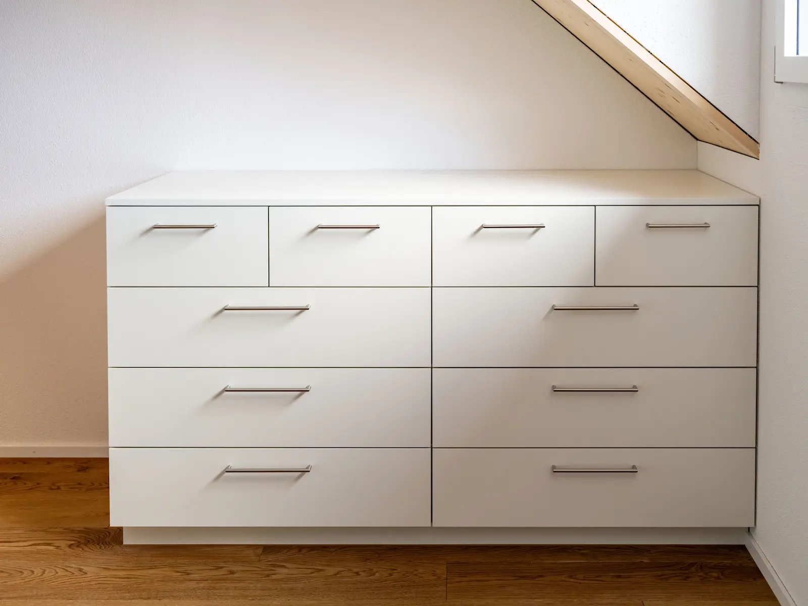Massgefertigtes Sideboard unter Dachschräge mit mehreren Schubladen, eingebaut im Mehrfamilienhaus Obstgarten