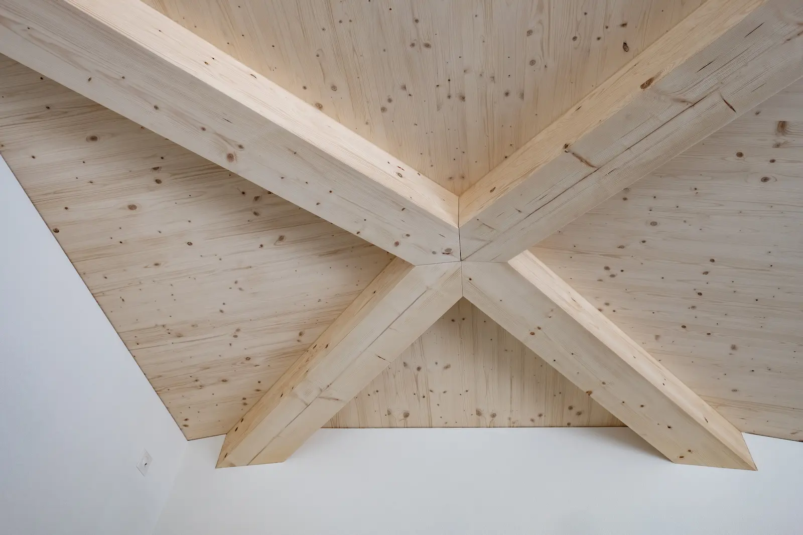 Verbindung der geneigten Holzträger im sichtbaren Zeltdach-Tragwerk aus Brettschichtholz, sorgfältig ausgeführt in Zimmermannsarbeit.