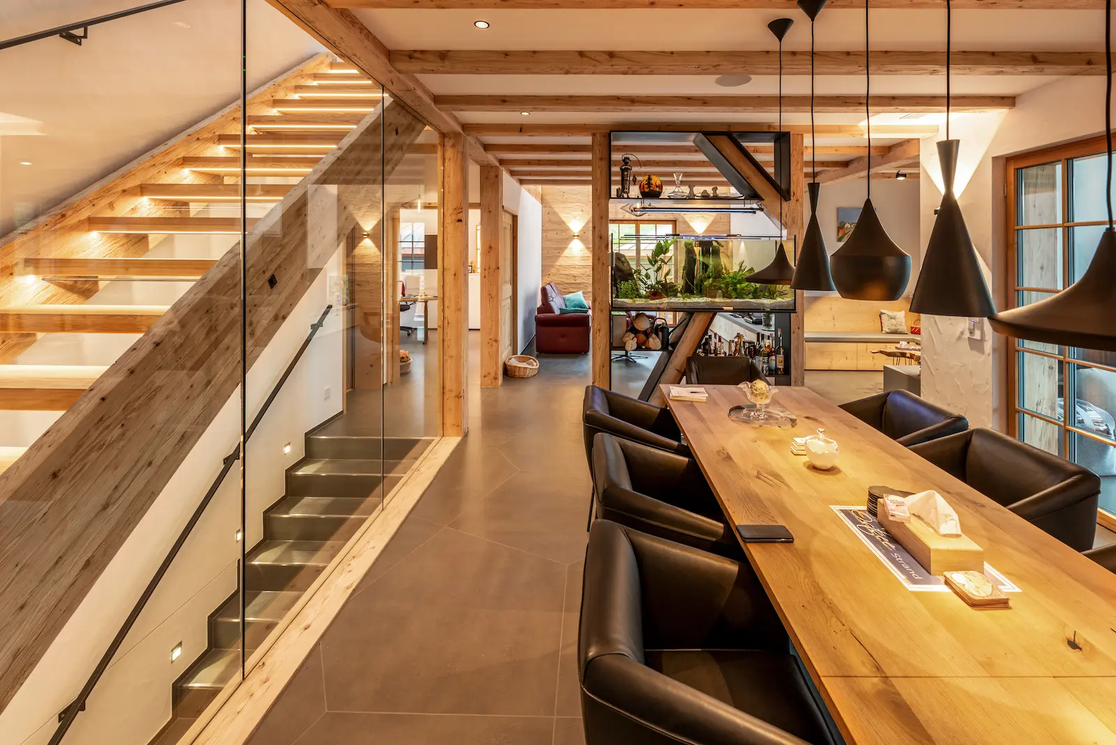 Lärchentreppe mit vollflächigem Glasgeländer als Absturzschutz und grosszügiger Verglasung für natürlichen Lichteinfall.