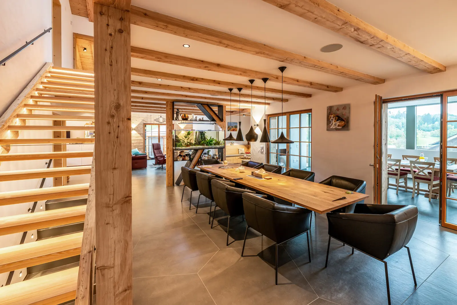Einläufige Treppe aus geschlagenem Lärchenholz mit Glasabsturzschutz, offener Bauweise und harmonischem Übergang zum Wohnraum.