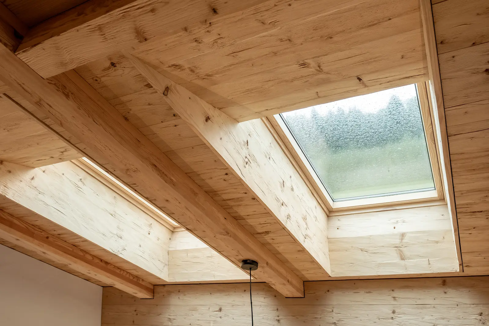 Detailansicht eines VELUX Dachfensters mit präzise eingepasstem Lärchenfutter und sichtbarer Holzmaserung.