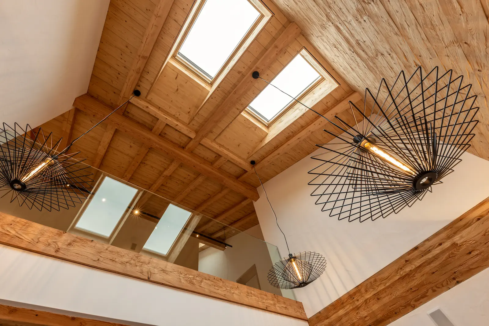 Mehrere VELUX Dachfenster in einer Lärchenholzdecke mit sichtbarer Balkenkonstruktion und integriertem Aussenrollladen.