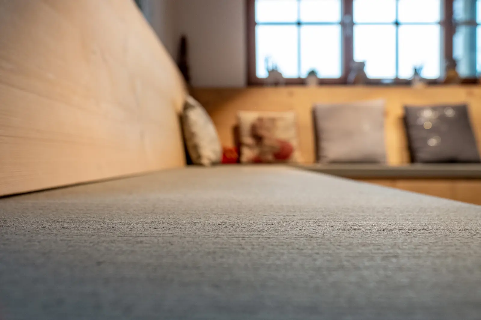 Sitzbankanlage mit grauer Steinplatte und umlaufender Holzverkleidung im offenen Wohnbereich.