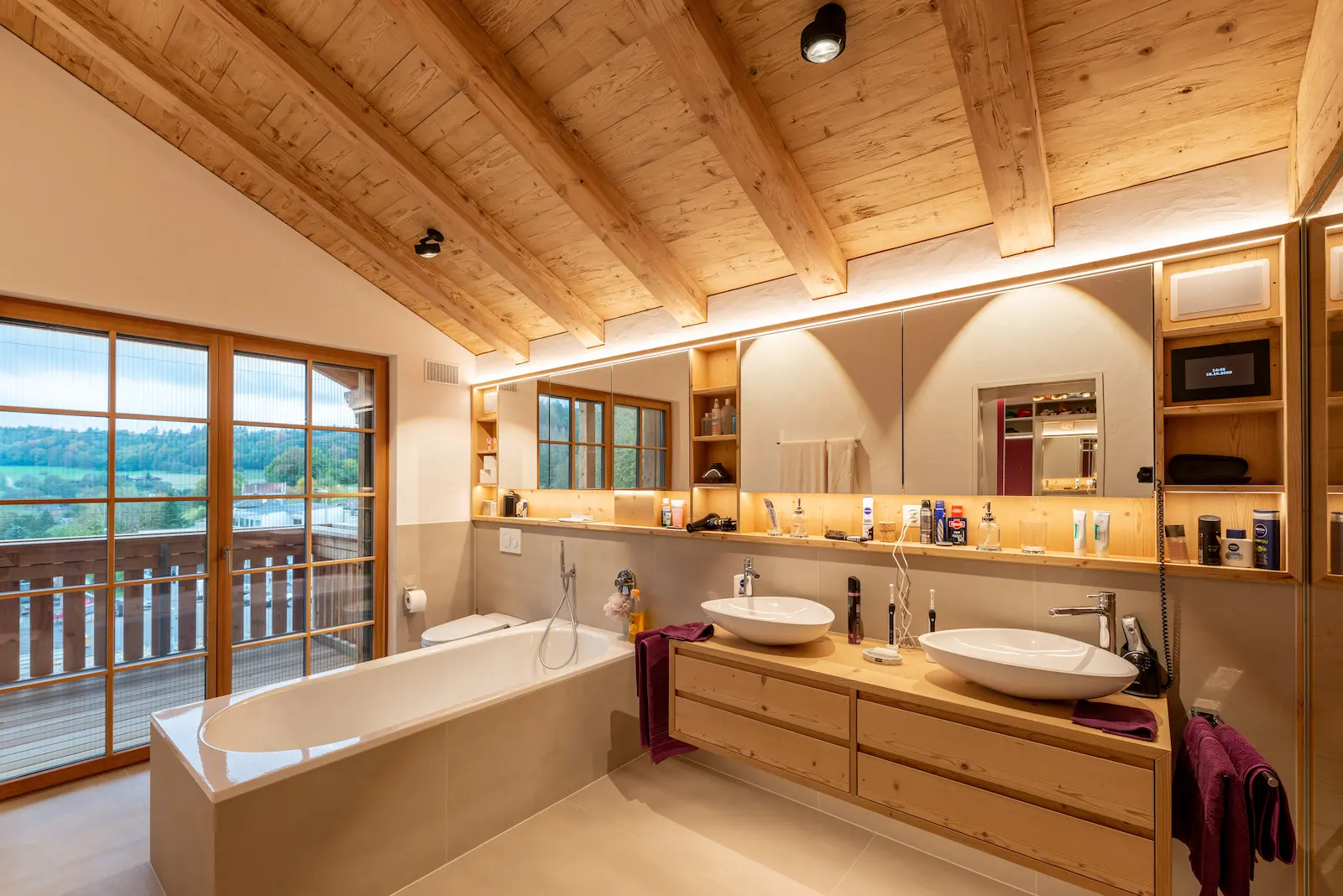 Modernes Badezimmer mit sichtbarer Lärchendecke, Holzmöbeln und Balkonzugang.