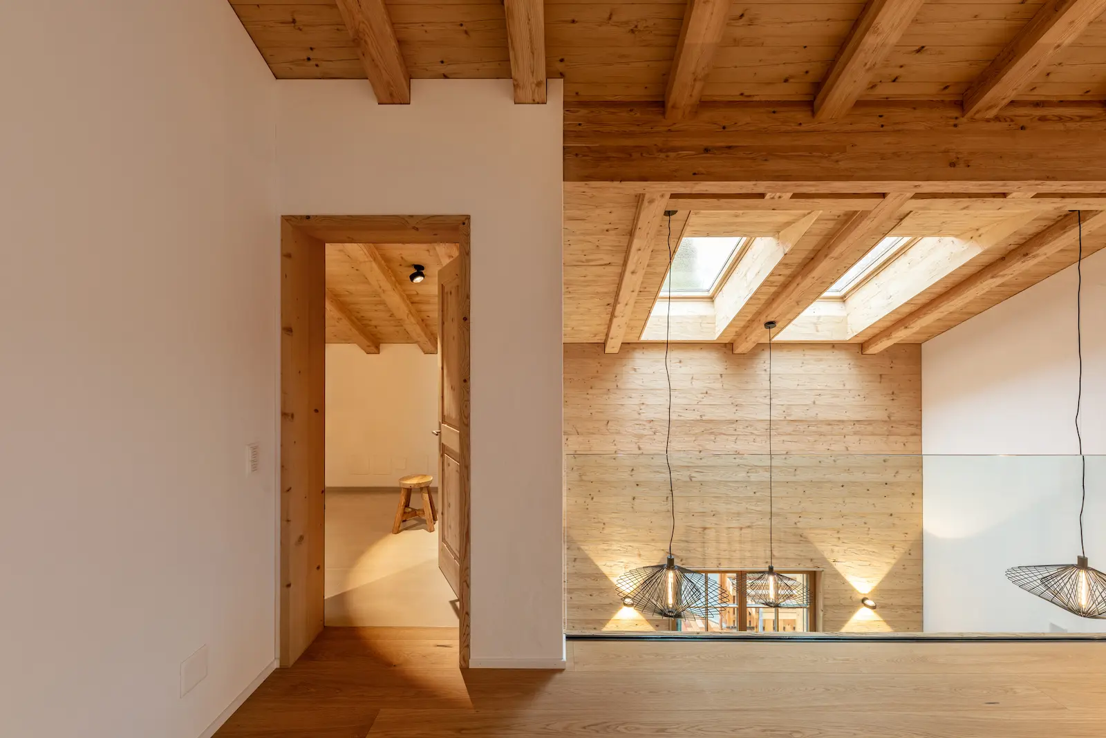 Galeriegeschoss mit sichtbarer Lärchendecke, Dachfenstern und Holzwandverkleidung.