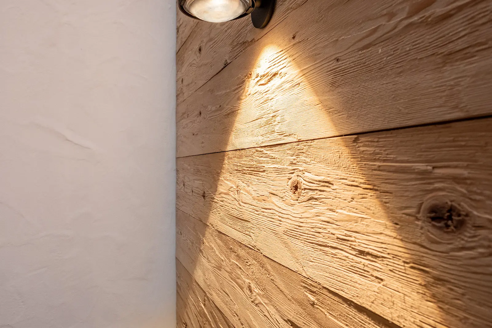 Wandverkleidung aus geschlagener Lärche mit sichtbarer Holzstruktur.