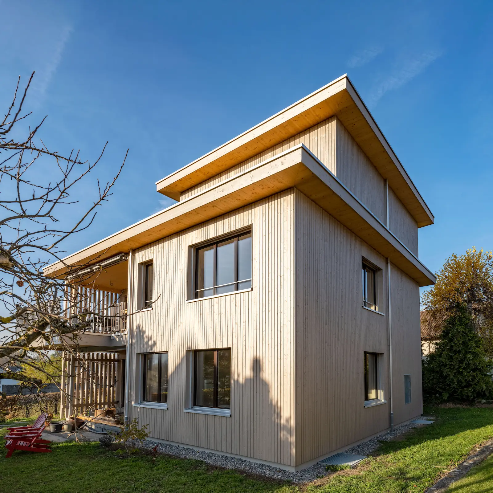 Detail der vertikal montierten Holzfassade über zwei Geschosse mit sichtbaren Lamellen und präzisen Anschlussdetails.