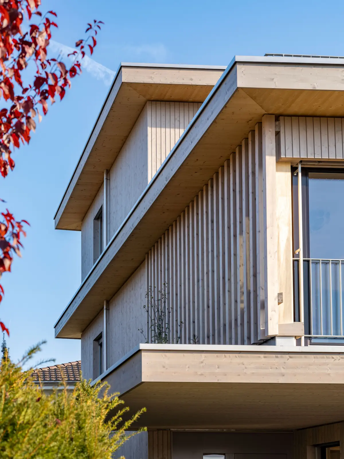 Frontansicht eines Einfamilienhauses mit überdachtem Carport und vertikaler Holzfassade aus behandelten Fichtenbrettern.