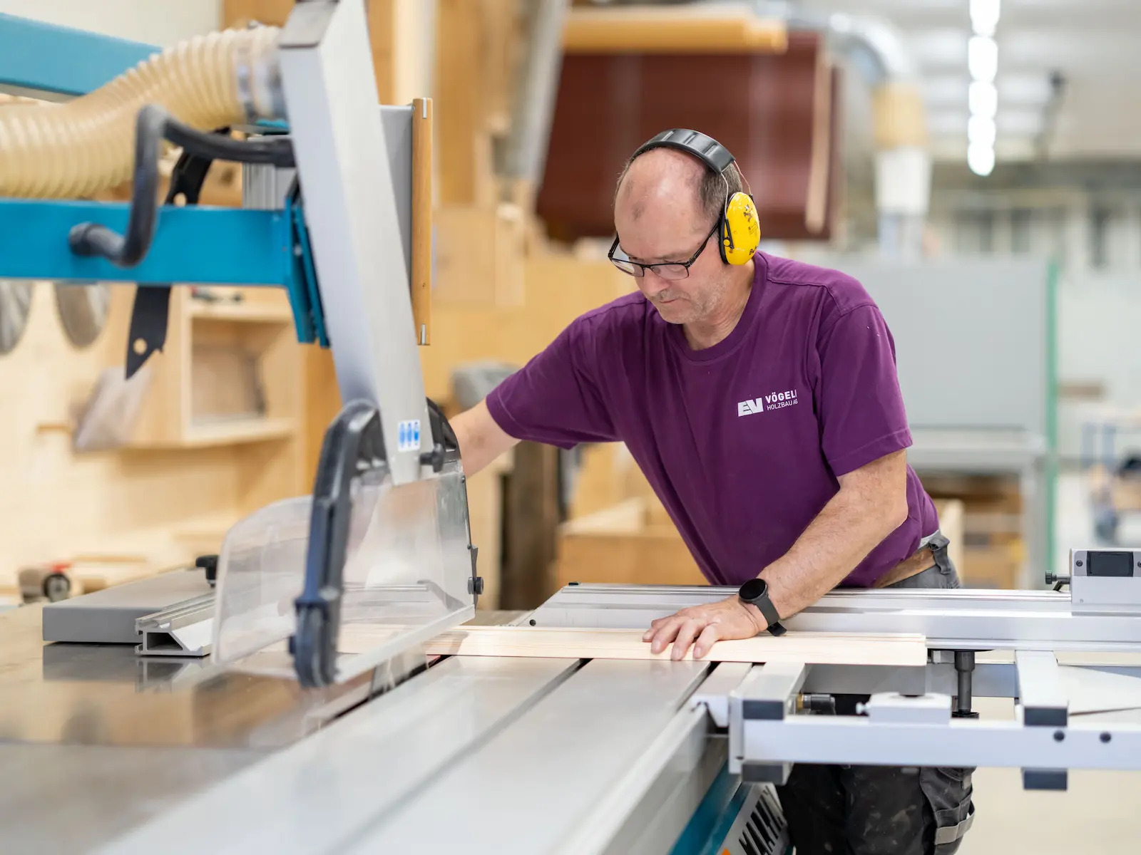 Präzises Handwerk bei Vögeli Holzbau AG: Ein Zimmermann an der Tischfräse — konzentriert, sorgfältig und mit dem richtigen Werkzeug für anspruchsvolle Holzarbeiten