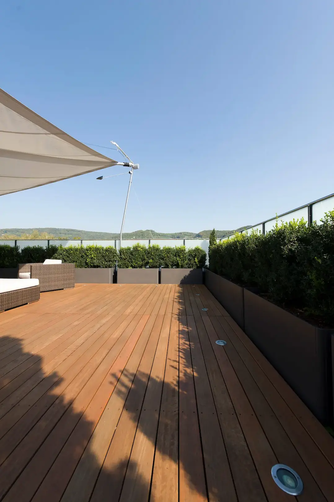 Terrasse eines Mehrfamilienhauses in Kleindöttingen mit neuem Terrassenboden aus Sipo-Holz, Sonnensegel und Loungemöbeln
