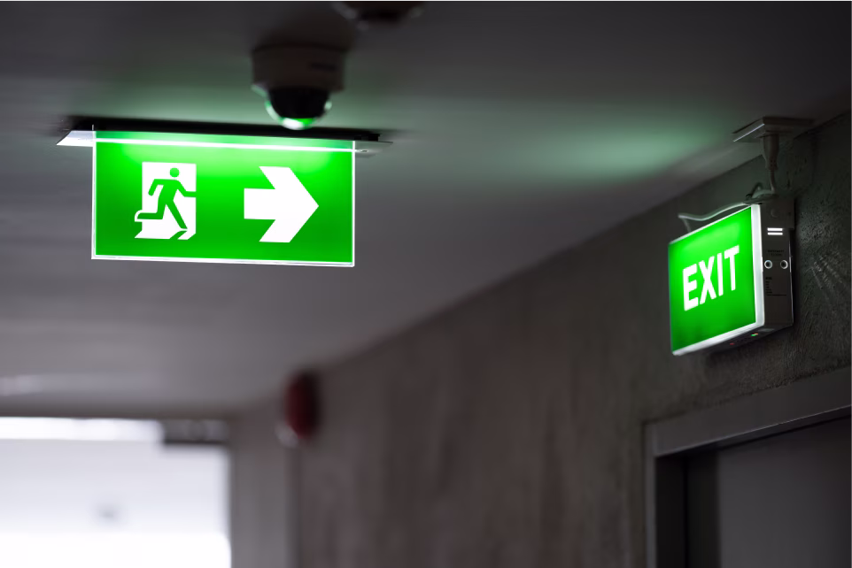 Green illuminated exit signs in a municipal building.