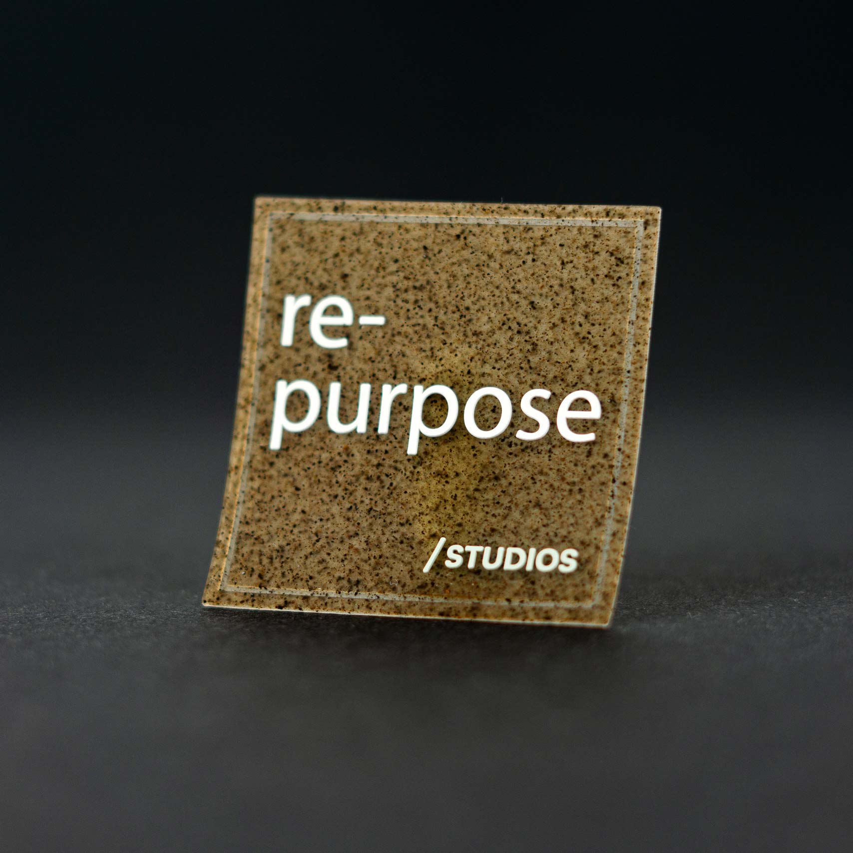 Textured square patch reading "re-purpose /STUDIOS"