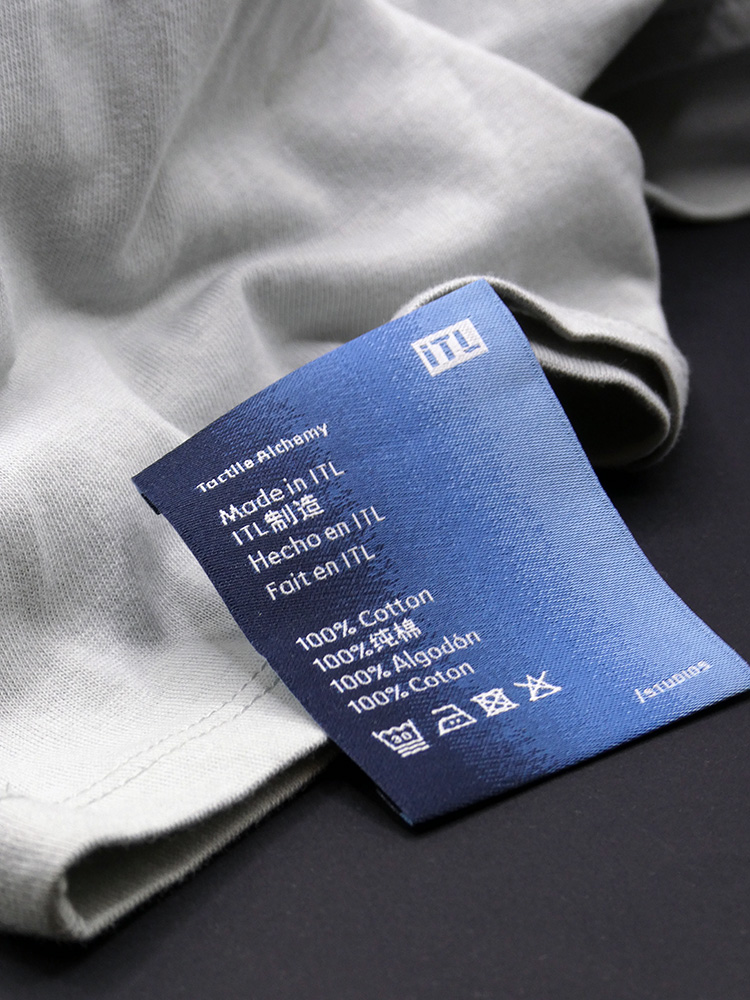 Blue printed care label reading "Made in ITL" in several languages, on a grey garment