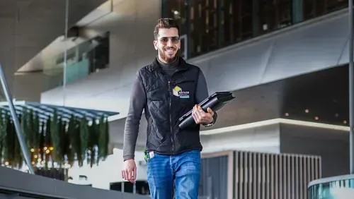 Geschäftsführer Rami Bayazid bei der Bauleitung, trägt Unternehmenslogo und Planungsmappe.