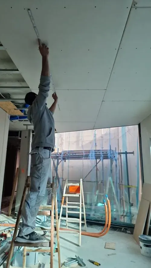Montagearbeiten an der Decke von einem Teammitglied im Trockenbau-Projekt.
