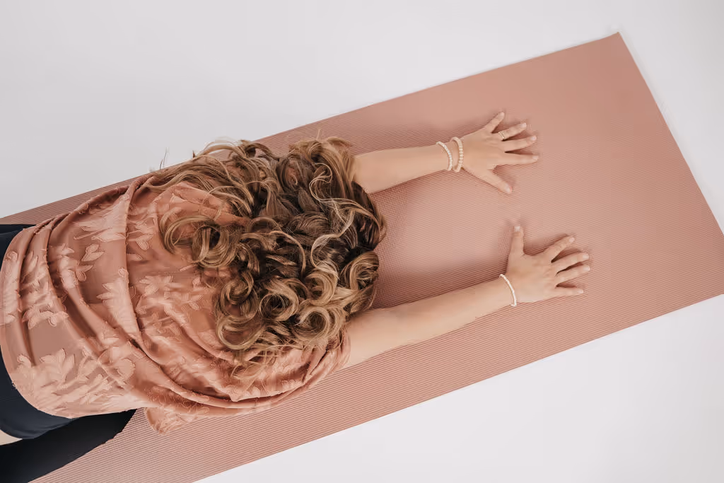 Frau macht Yoga im Kindhaltung auf einer rosa Yoga-Matte, Ansicht von oben.