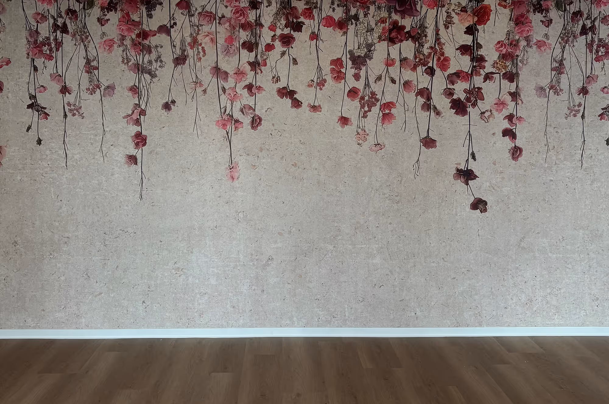 Zimmer mit Holzboden und Wanddekor aus hängenden roten und rosa Blumen.