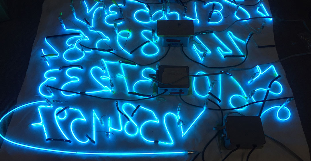Clear Blue Argon glass numbers in reverse on work bench ready to be cleaned.
