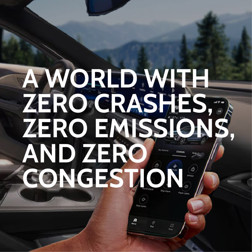 General Motors myCadilllac mobile app open on a phone being held in front of the Cadillac Lyriq infotainment system with  mountains in the background