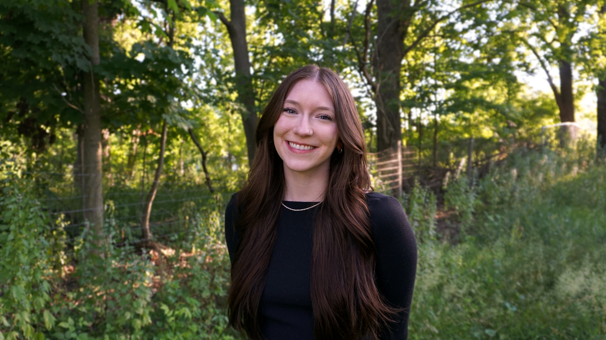 Headshot of Kaileigh smiling with trees in the background