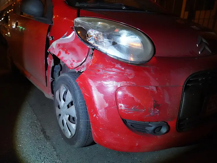 Frontschaden an einem roten Kleinwagen, Schadenaufnahme am Unfallort bei Nacht