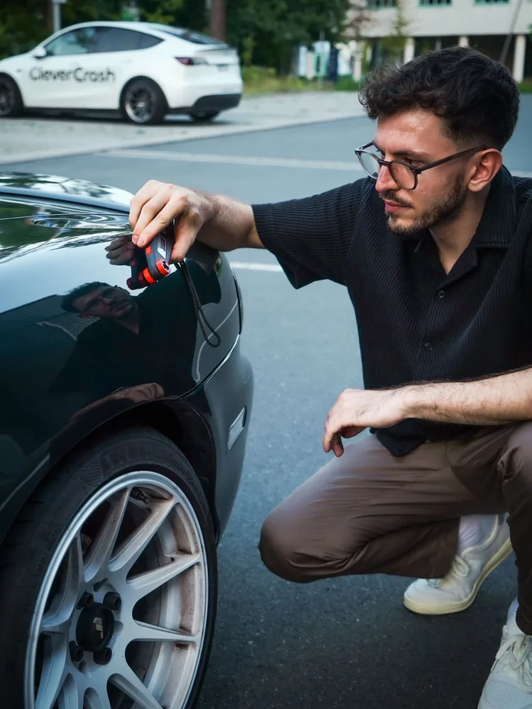 Maximilian Fromm misst die Lackschichtdicke an einem Fahrzeug
