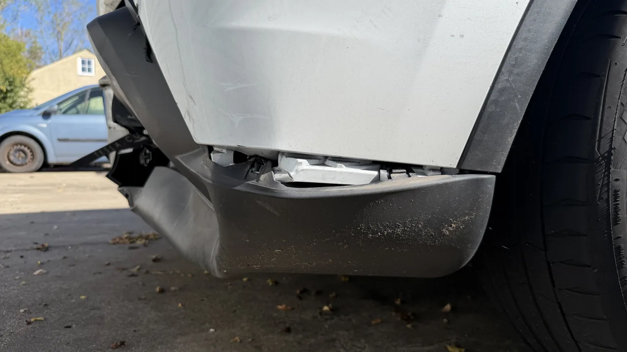 Verschobene, gerissene Stoßfängerecke hinten an einem Tesla Model Y, dahinter die Halterung der Crashstruktur