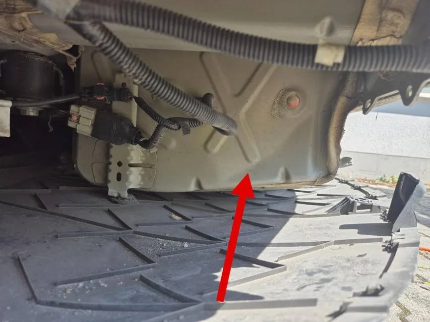 Vergleichsbild: Unterboden hinten an einem Tesla Model 3 nach Heckanprall, Pfeil auf die Anstoßstelle