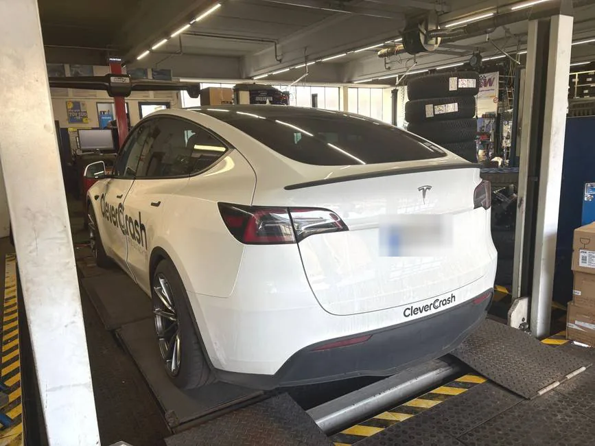 Der weiße Tesla Model Y von CleverCrash mit Firmenbeschriftung in einer Werkstatt