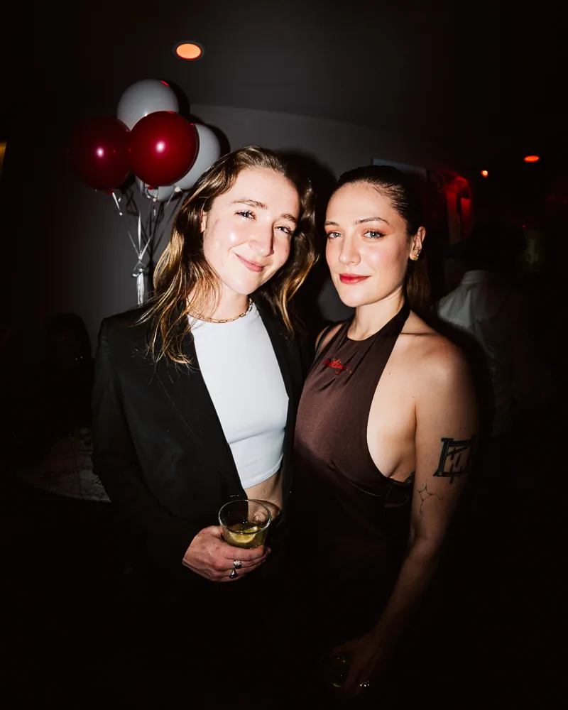Two friends at the Edition 3 launch party, lit by flash