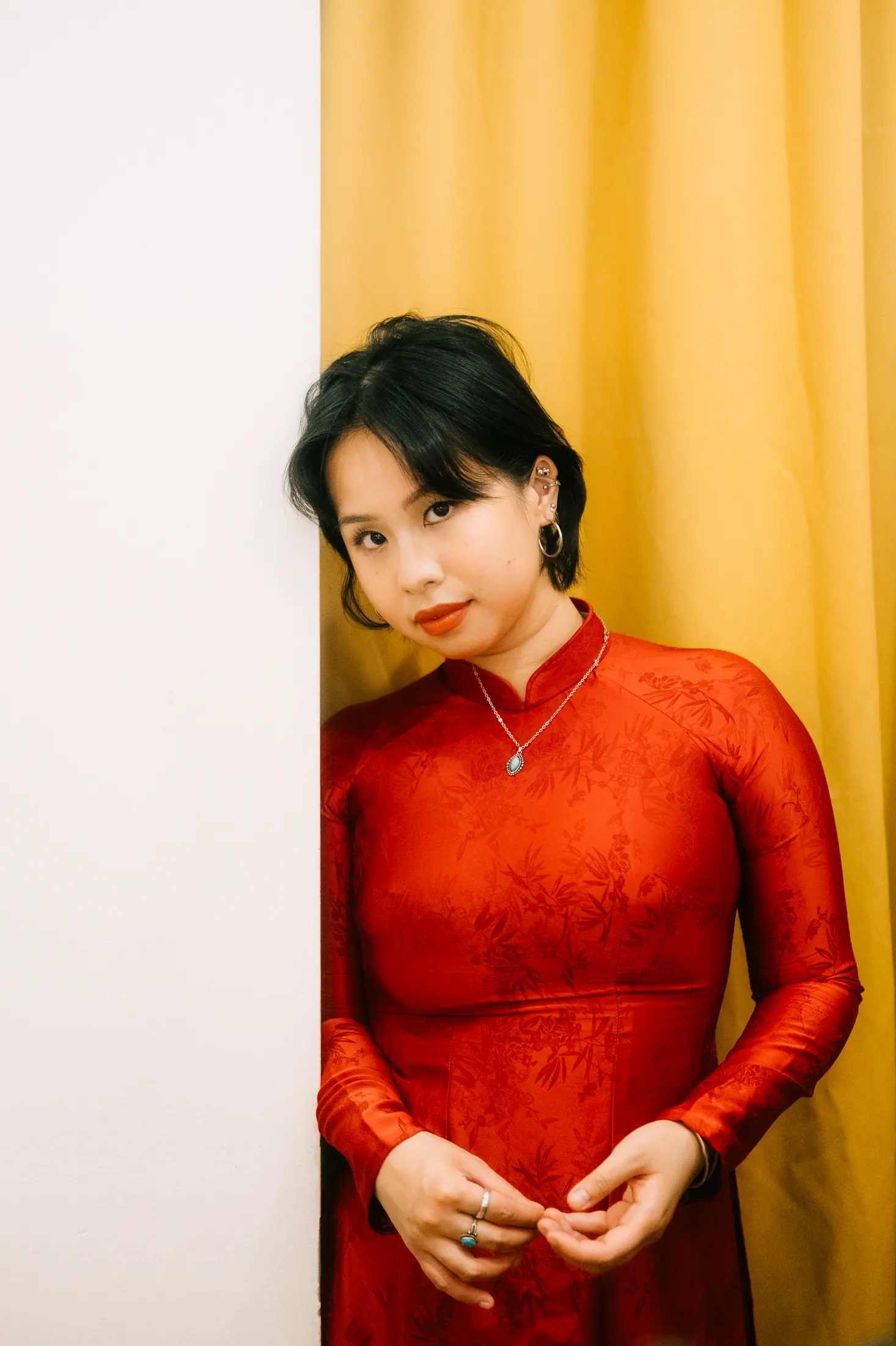 Trà My Truong in red against a mustard curtain
