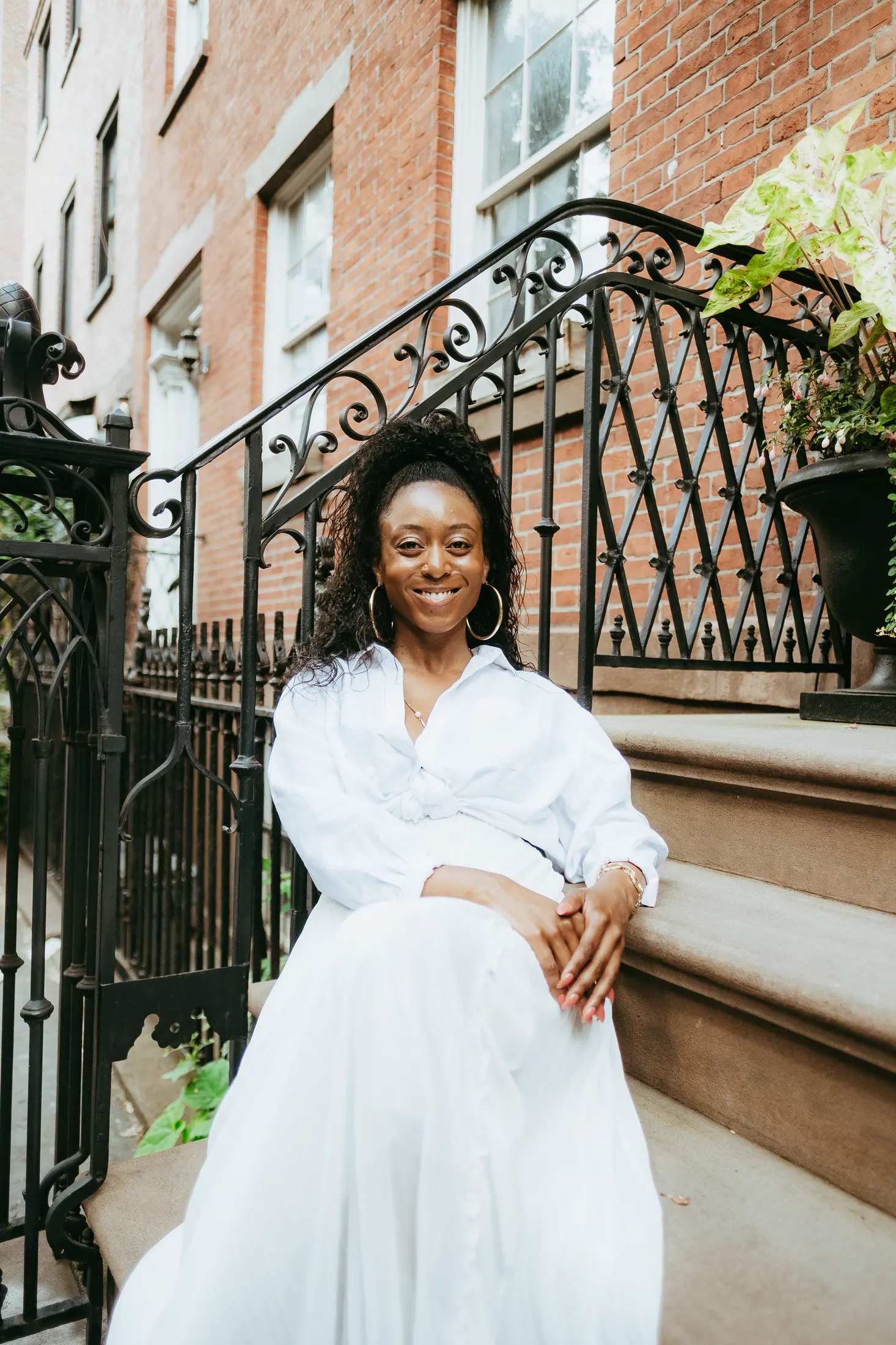 Branden Janese in white on a brownstone stoop