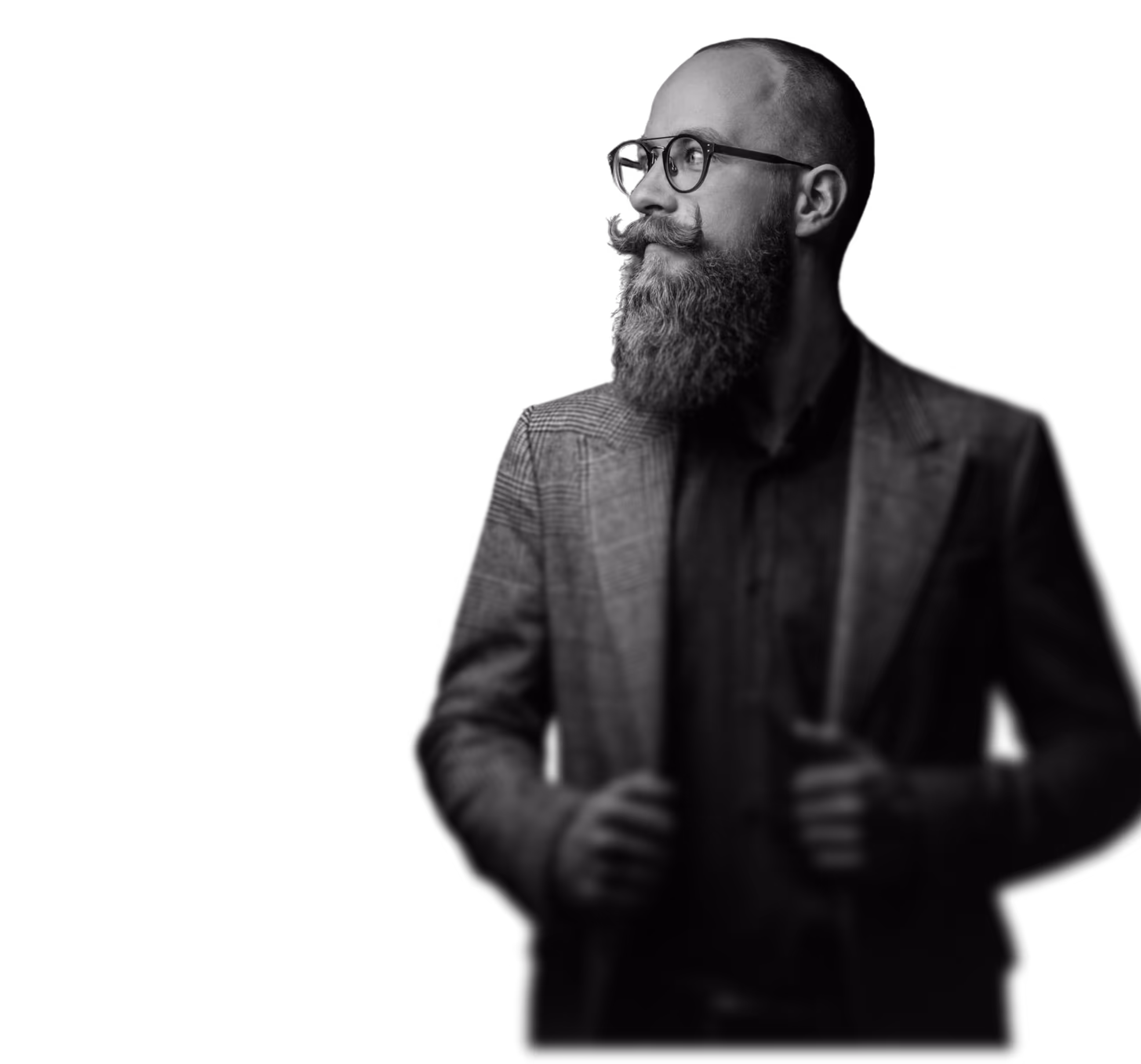 Black and white image a man with glasses and a long beard, holding his hands in his jacket's pockets