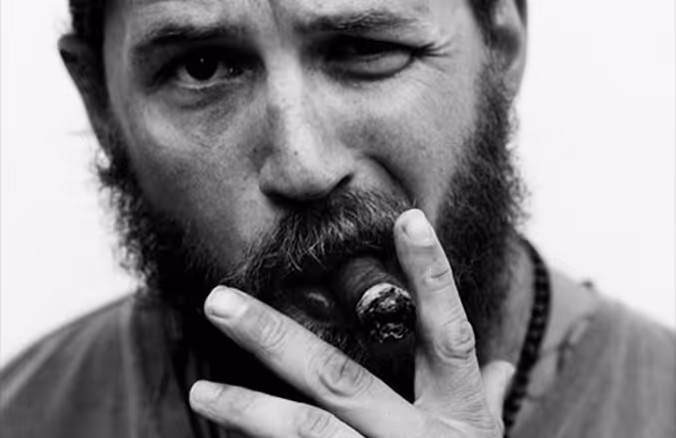 Black and white image of a bearded man smoking a cigar