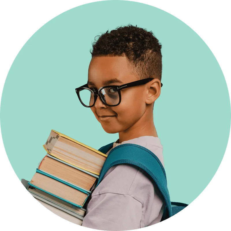 A young boy with glasses holding a stack of books.