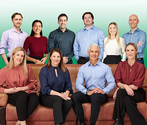 A team of nine Peak Podiatry professionals, some sitting on a couch and others standing behind them.