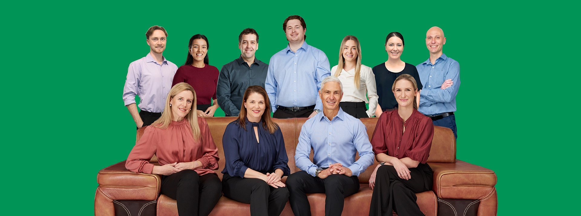 A team of eleven Peak Podiatry professionals, some sitting on a couch and others standing behind them.