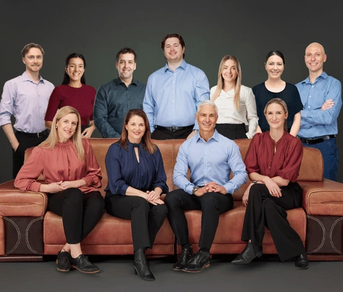 A team of eleven Peak Podiatry professionals, some sitting on a couch and others standing behind them.