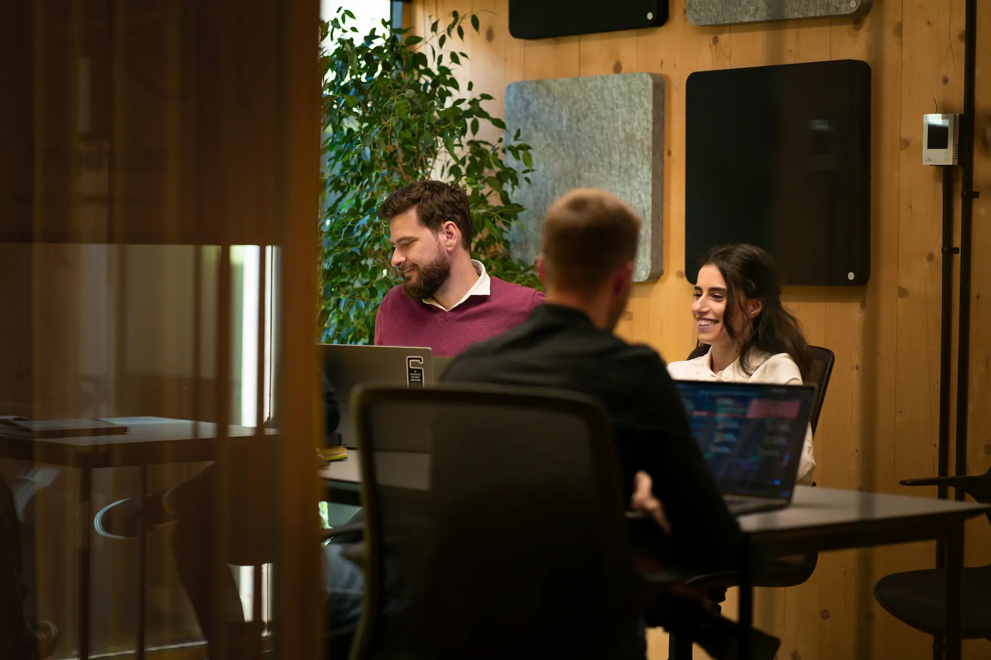 A group of people sitting around a table with laptops