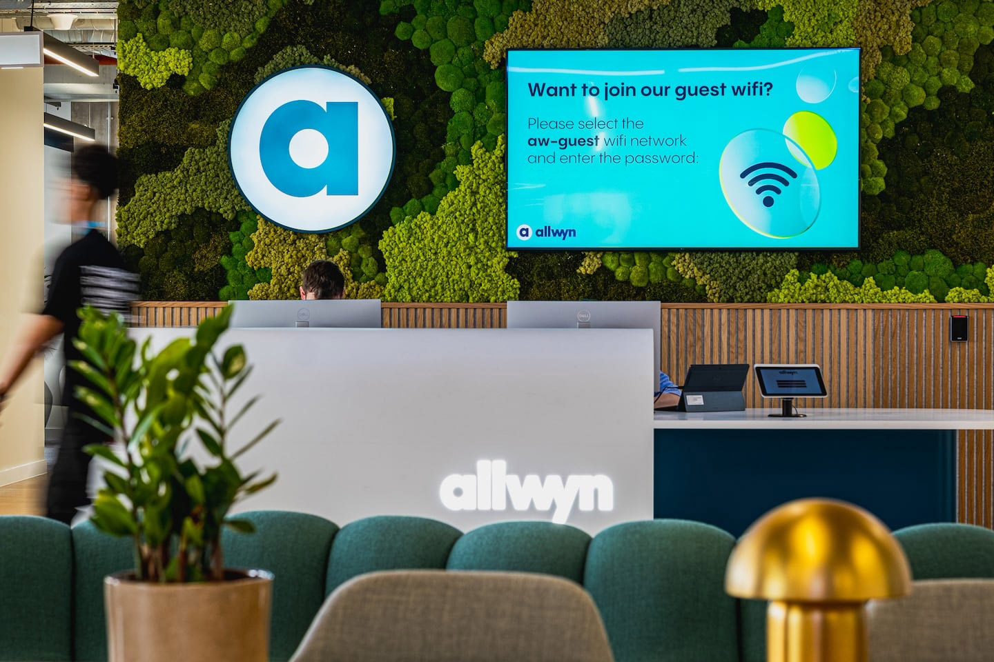 This image shows a person applying makeup on another person’s face. The person getting the makeup done has bright, colorful makeup on their eyes and a flag design on their cheek. The one applying the makeup is smiling and looking at the camera. There’s a sense of fun and creativity in this moment.