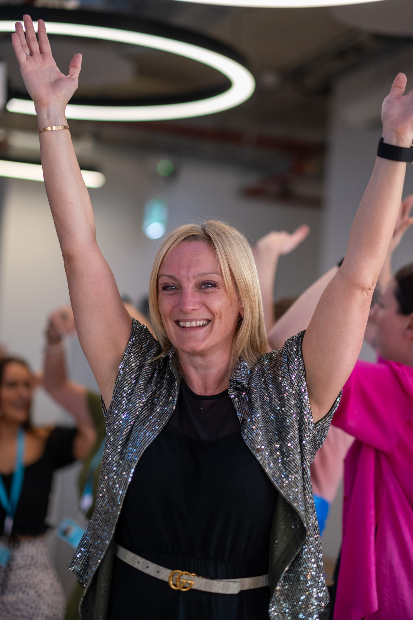 An audience at an event clapping and cheering enthusiastically. The crowd looks engaged, with some people laughing and smiling while applauding.