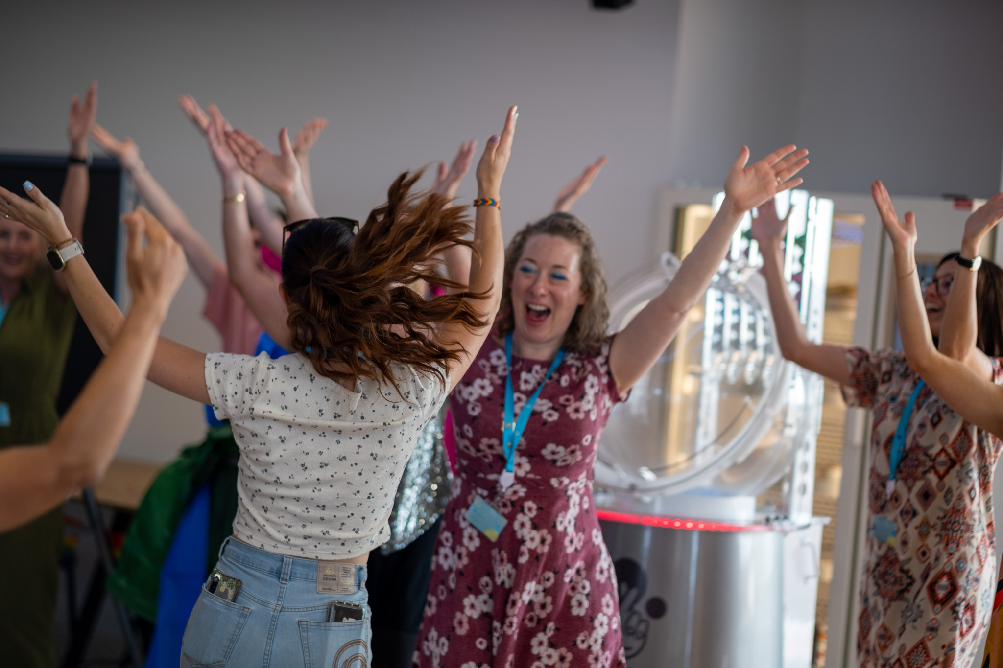 An audience at an event clapping and cheering enthusiastically. The crowd looks engaged, with some people laughing and smiling while applauding.