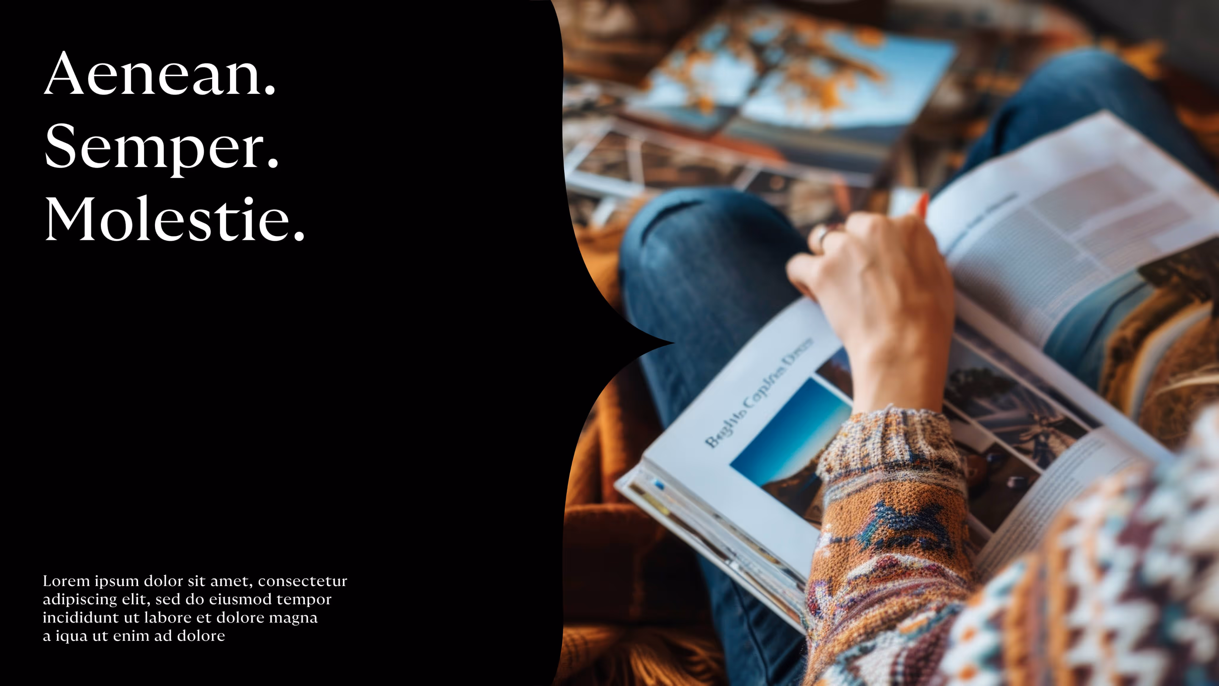 Person wearing a patterned sweater reading a magazine while sitting with folded legs.