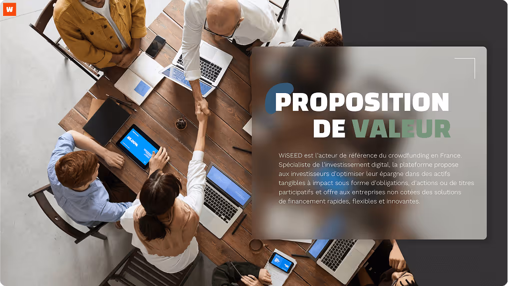 Slide PowerPoint avec des professionnels assis autour d'une table en bois se serrant la main lors d'une réunion, avec des ordinateurs portables et tablettes sur la table.