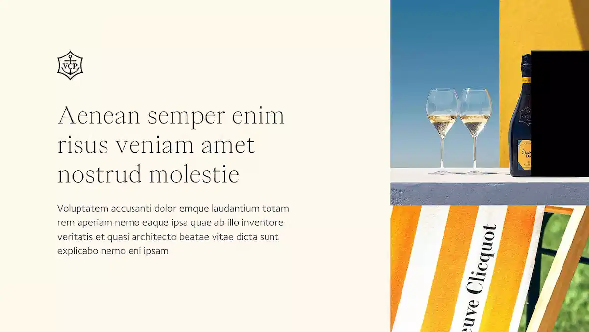 Deux verres de champagne et une bouteille Veuve Clicquot sur une table blanche avec une chaise rayée orange et blanche.