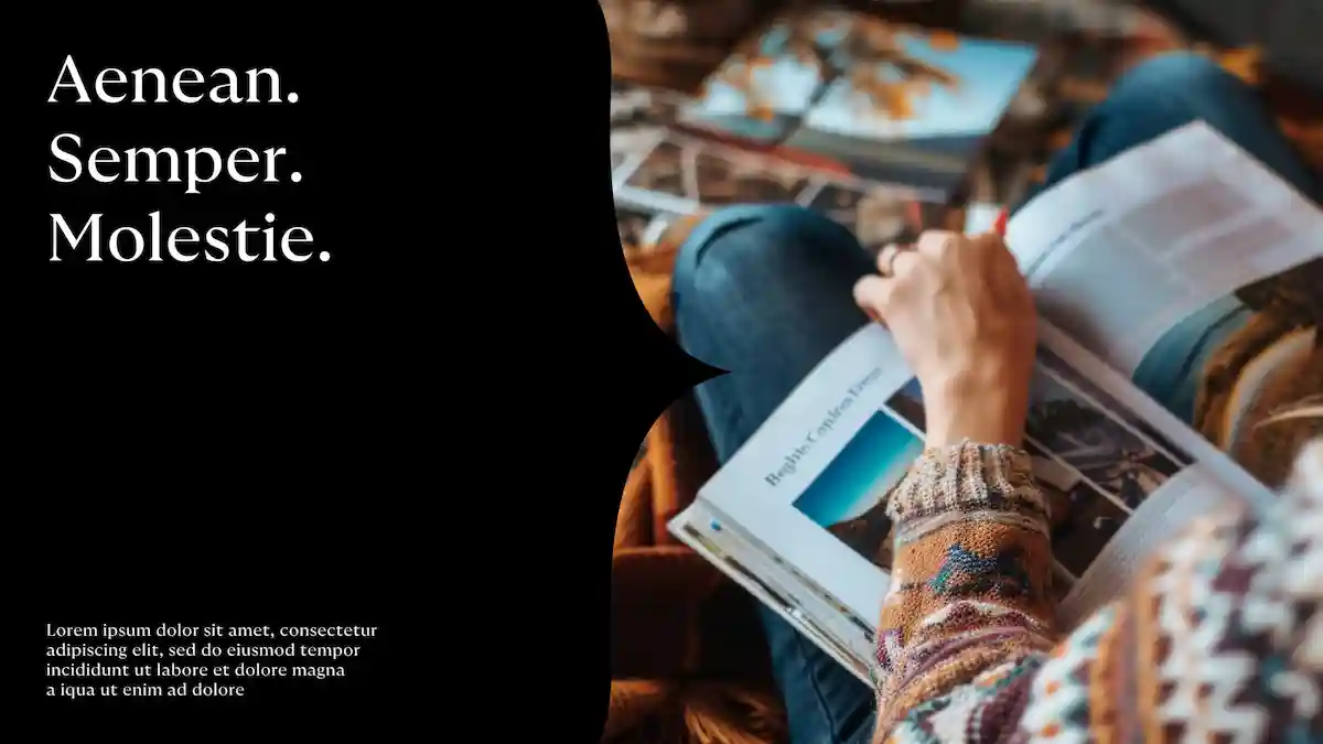 Personne lisant un magazine avec photos, portant un pull coloré, assise jambes croisées.