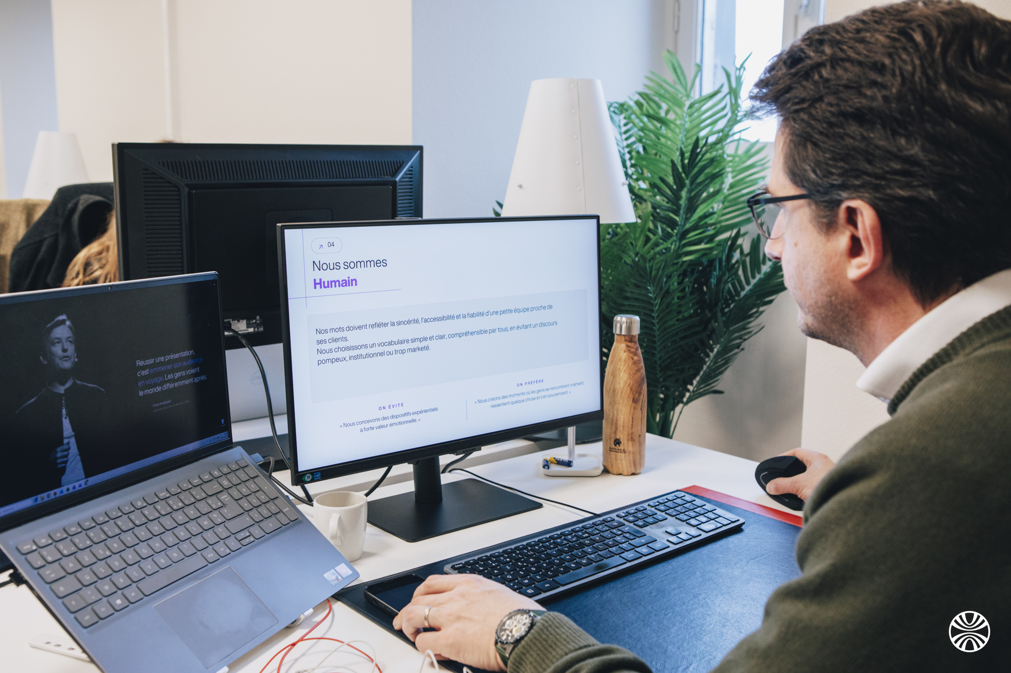 Homme qui regarde son écran professionnel dans un bureau sur lequel il est inscrit "Nous sommes Humain"