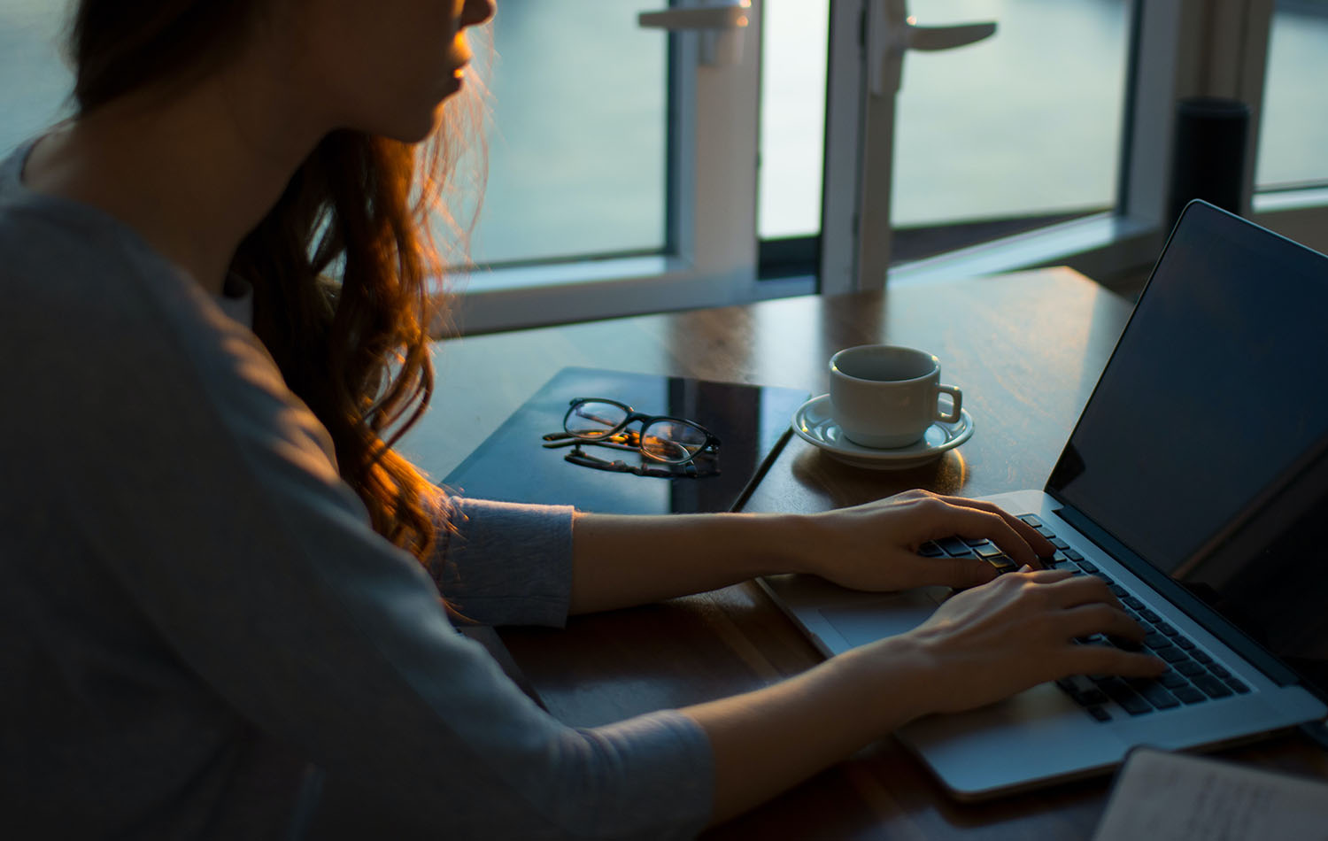 A woman sat at her desk writing on her laptop
