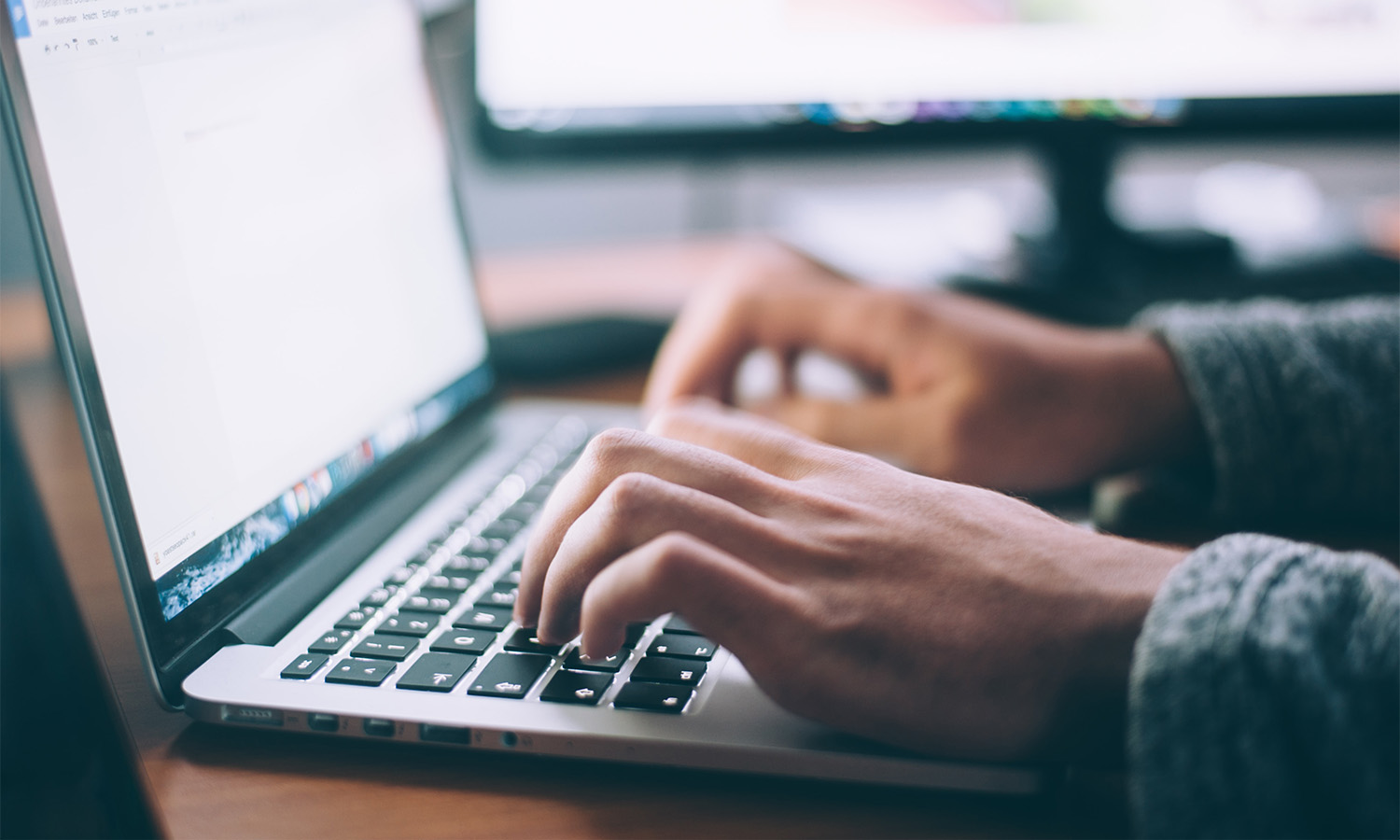 A close up of a person's hands typing onto a laptop
