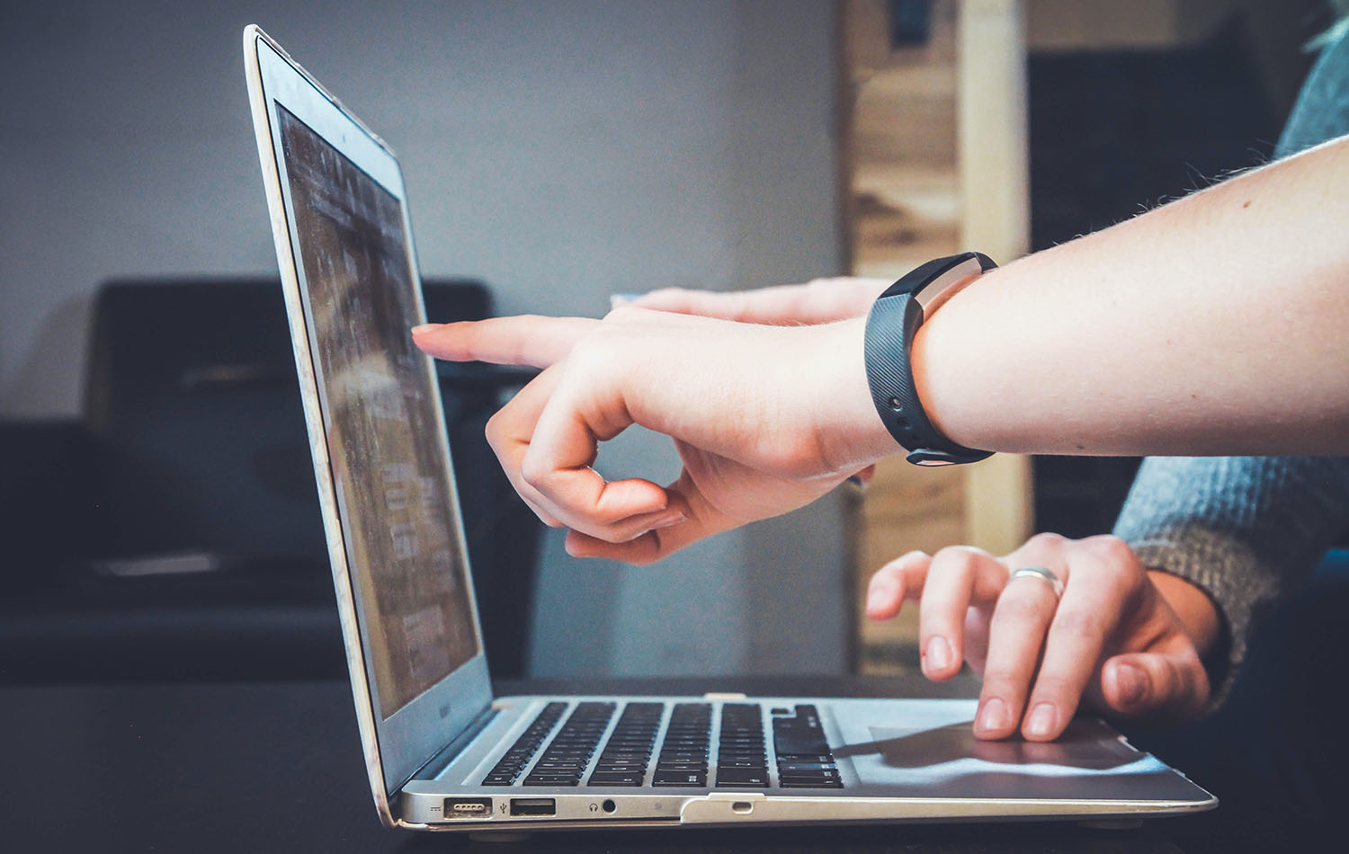 Two people pointing at a laptop screen